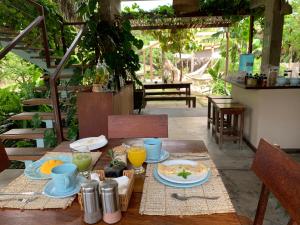 uma mesa de madeira com pratos de comida e bebidas em Vila das Águas em Atins