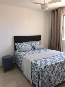 a bedroom with a bed with a floral bedspread at Apartamento em Aracaju a 5 minutos da praia in Aracaju