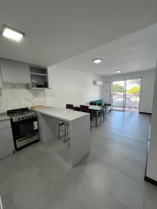 a white kitchen with a counter top and a table at Departamento del Río in Paraná
