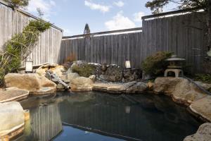 a pool of water in front of a wooden fence at Onyado Hisui in Takayama