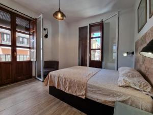 a bedroom with a bed and a chair and windows at Exclusividad a Pie de la Torre de la Catedral in Granada