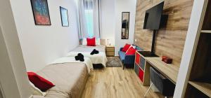 a room with two beds with red pillows and a tv at Gran apartamento ideal grupos muy cerca Barcelona in Badalona