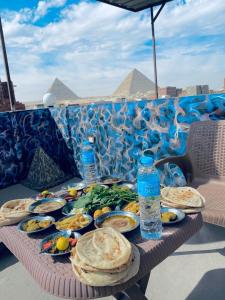 Horus Pyramids Inn في القاهرة: طاولة بها صحون من طعام وزجاجات ماء