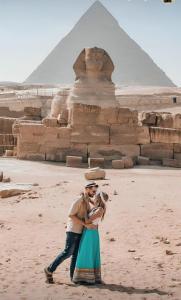 een man die een vrouw vasthoudt voor de piramiden bij Horus Pyramids Inn in Caïro