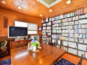 a library with a table and a tv and books at 万葉茶寮みさか in Hirugami