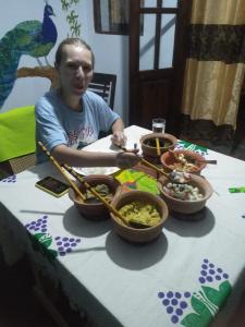 a man sitting at a table with bowls of food at Mirissa Jungle view in Mirissa