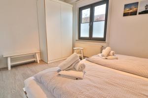 2 łóżka w pokoju z 2 krzesłami i oknem w obiekcie Süderdüne w mieście Langeoog
