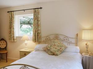 a bedroom with a white bed with a window at The Cottage in Fressingfield