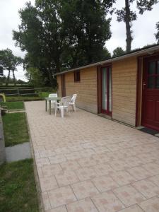 een patio met 2 stoelen en een tafel voor een gebouw bij Les Ecuries du Préchard in La Chapelle-Chaussée