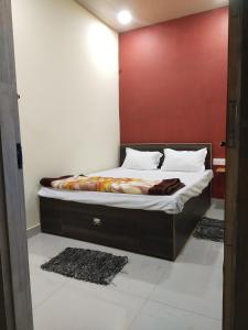 Posto letto in camera con parete rossa. di OYO Diamond Guest House a Rudrapur