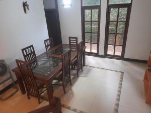 a dining room with a table and chairs and windows at Sanuki Villa in Hikkaduwa