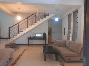 a living room with a couch and a staircase at Sanuki Villa in Hikkaduwa