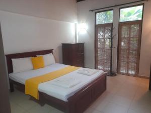 a bedroom with a large bed with yellow and white sheets at Sanuki Villa in Hikkaduwa