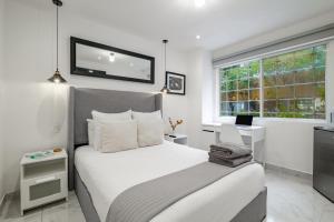 a white bedroom with a bed and a window at Leib 65 in Mexico City