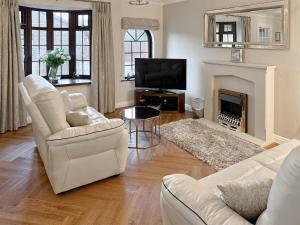 a living room with white furniture and a fireplace at Cleets Retreat in Seahouses