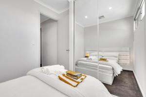 a white bedroom with two beds and a mirror at 96B Esplanade, Semaphore in Semaphore