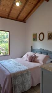 um quarto com uma cama com lençóis cor-de-rosa e uma janela em Pousada Vilarejo das Oliveiras em Queimada