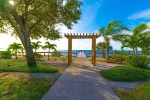 a pathway with a wooden arch and palm trees at Beautiful New Luxury Townhome with Private Beach and Swimming Pools in Ruskin