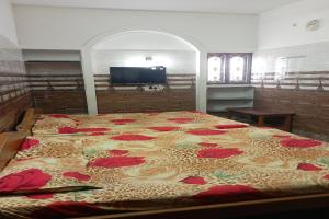 Un dormitorio con una cama grande con flores rojas. en OYO Sunrise Residency en Palani