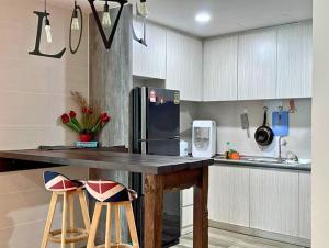 a kitchen with a counter with a refrigerator and stools at DS VivacityMall Jazzsuite 0902 in Kuching