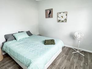 a bedroom with a bed and a fan at Little Mirror Bay in Laurieton