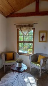 a living room with two chairs and a window at Pousada Vilarejo das Oliveiras in Queimada