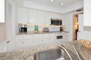 una cocina con armarios blancos y fregadero en Royal Palm Penthouse #5, en Vero Beach