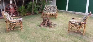 due sedie e un tronco d'albero nell'erba di Chácara Pingo de Ouro a Salto Grande