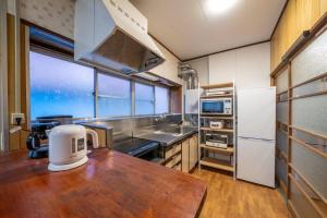 a kitchen with a wooden table and a refrigerator at Seaside House Nagi in Itoigawa