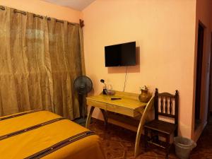 a bedroom with a desk with a television and a bed at Casa Esperanza in Panajachel