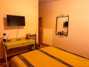 1 dormitorio con cama, escritorio y espejo en Casa Esperanza, en Panajachel