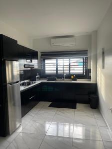 een keuken met zwarte kasten en een roestvrijstalen koelkast bij Luxe appartementen Paramaribo Noord in Paramaribo