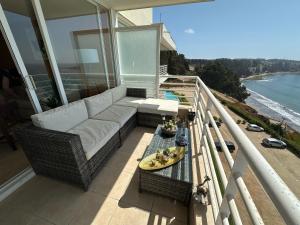 un sofá y una mesa en un balcón con vistas al océano en Condominio Alto Mar, en Puchuncaví