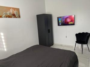 een slaapkamer met een bed en een tv aan de muur bij Luxe appartementen Paramaribo Noord in Paramaribo