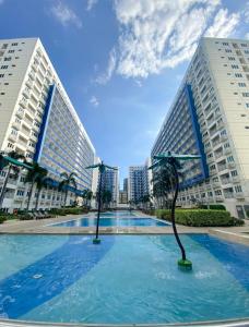a large swimming pool with two tall buildings at Madison Place at Sea Residences powered by Cocotel in Manila