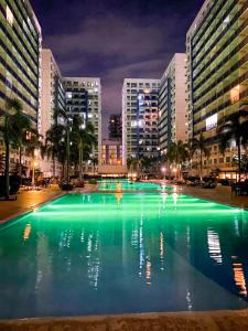 a large pool of green water in a city at night at Madison Place at Sea Residences powered by Cocotel in Manila