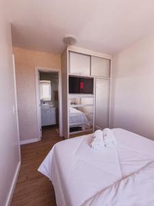 a bedroom with a white bed and a tv at Apto novo com vista para o mar e piscina in Laguna +17 photos
