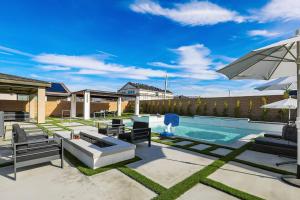 um quintal com uma piscina com mobiliário de pátio e um guarda-sol em Canneto Way - Large villa w/ a large backyard em Indio