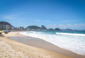 een strand met de oceaan en gebouwen op de achtergrond bij Studio na quadra da praia de Copacabana in Rio de Janeiro