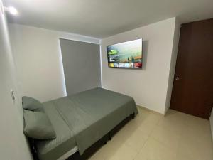 ein Schlafzimmer mit einem Bett und einem TV an der Wand in der Unterkunft Apartamento en Prados del Este Amplio comodo y equipado in Cúcuta