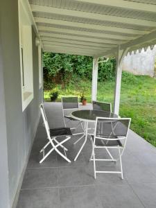 een patio met een tafel en stoelen op een veranda bij Maison ika in Le François