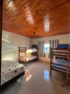 een slaapkamer met 2 bedden en een houten plafond bij Chácara Gama em condomínio Igarata-SP - Jacuzzi com hidromassagem, piscina e sauna in Igaratá