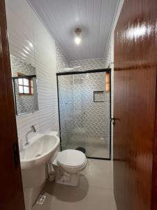 La salle de bains est pourvue de toilettes, d'un lavabo et d'une douche. dans l'établissement Chácara Gama em condomínio Igarata-SP - Jacuzzi com hidromassagem, piscina e sauna, à Igaratá