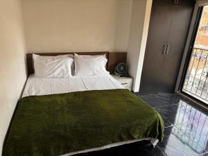 a bedroom with a bed with a green blanket on it at Aparta Suite Torre De Prado 501 in Medellín