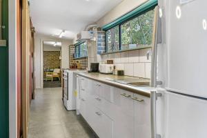 a kitchen with white cabinets and a large window at The Bunker - Orange, NSW in Mullion Creek