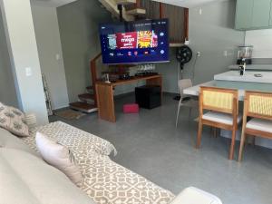 ein Wohnzimmer mit einem Sofa, einem TV und einem Tisch in der Unterkunft Área Nobre in Garopaba