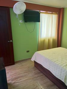 1 dormitorio con 1 cama y una pared con ventilador en Cardos hostal, en Pisco