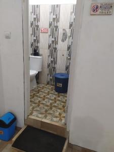 a bathroom with a toilet and a tile floor at Ador 46 Homestay Syariah & Kost in Mergan