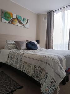 um quarto com uma cama com almofadas e uma janela em Departamento Ovalle 305 Quipu em Ovalle