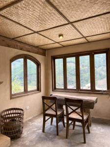 a room with a table and two chairs and windows at DE MONG SAPA in Sa Pa